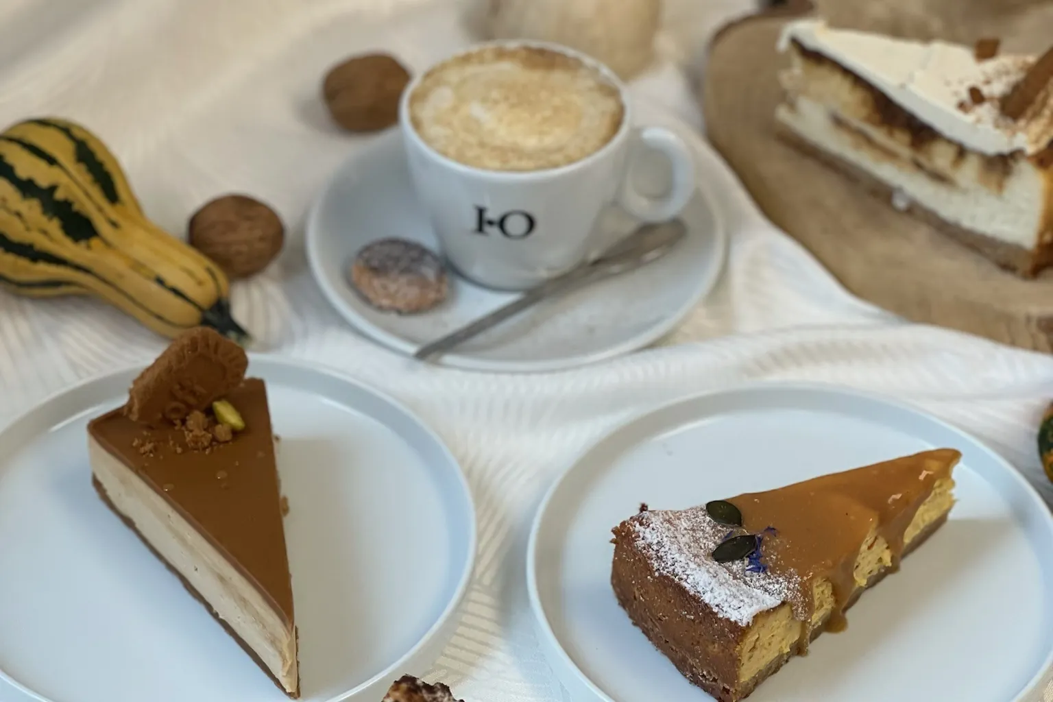 Saison-Torten mit Cappuccino und Zierkürbissen auf einem herbstlichen Kaffeetisch