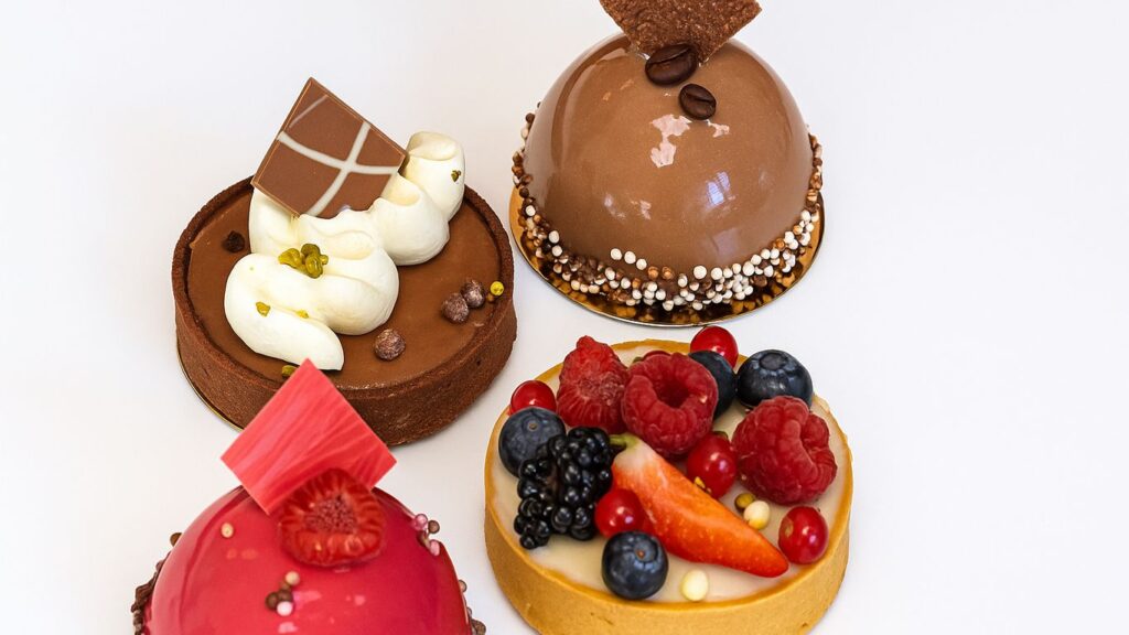 Four beautifully decorated pastries with chocolate, fruit, and cream.
