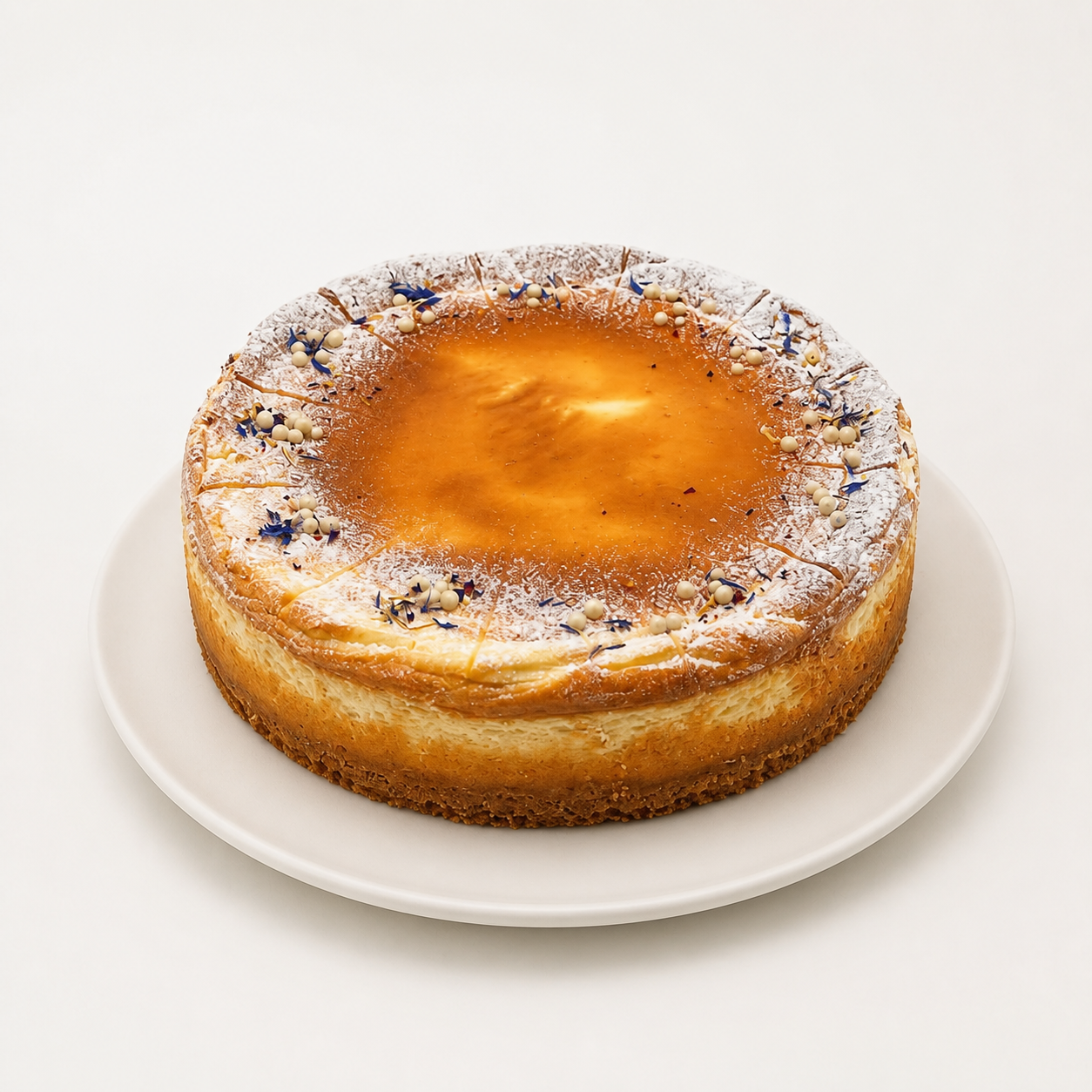 Karamell Cheesecake Karamell Cheesecake mit Schokoladendekor und Karamellkugeln auf weißem Teller vor fast weißem Hintergrund